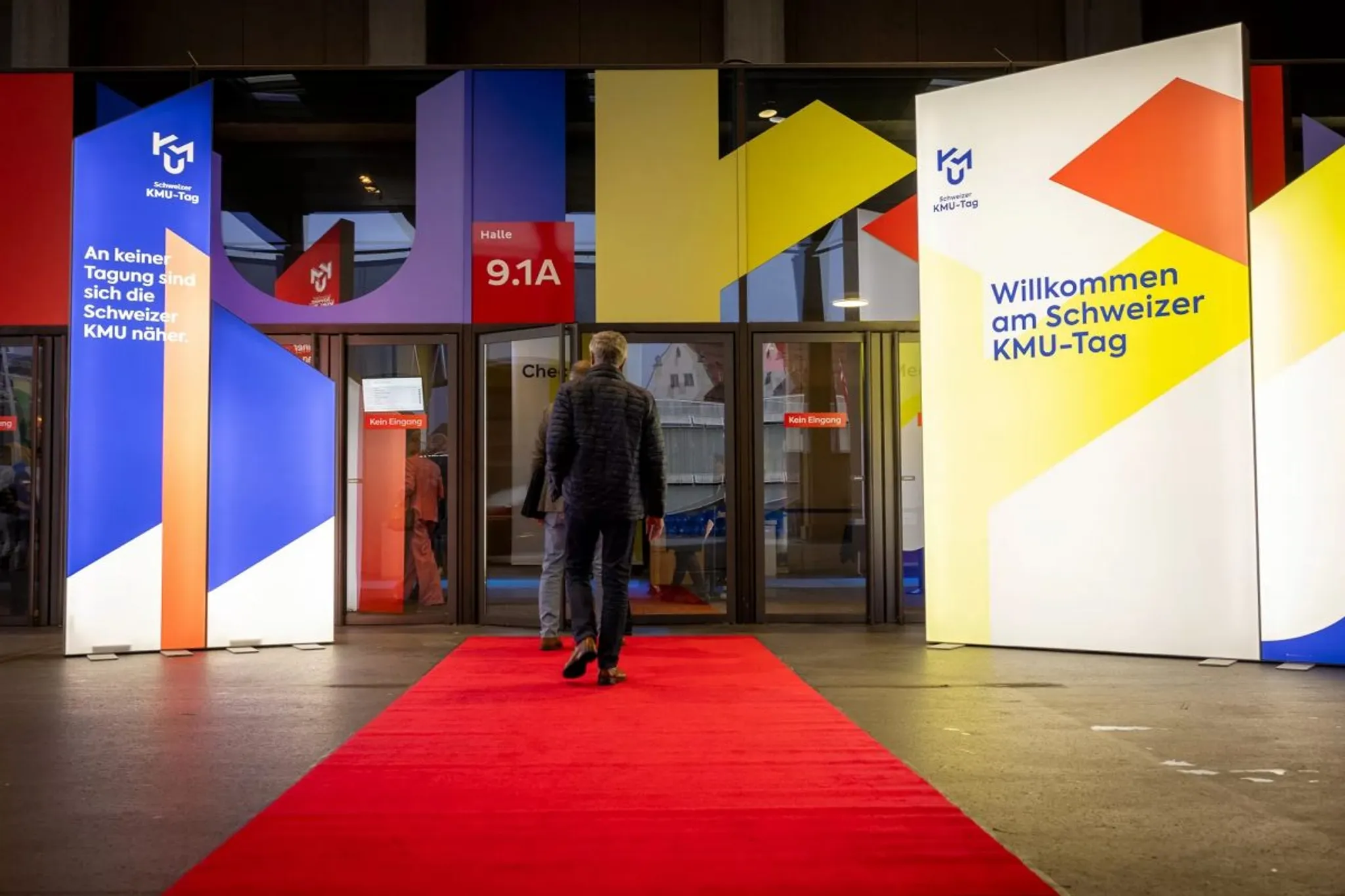 Entrance to Swiss SME Day 2024 with colorful event signage and a red carpet
